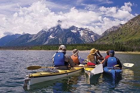Kayakers paddling on Jackson Lake with the Grand Tetons in the background