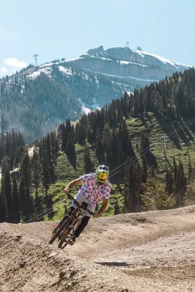 Downhill mountain biker ripping a dirt berm above Jackson Hole Mountain Resort