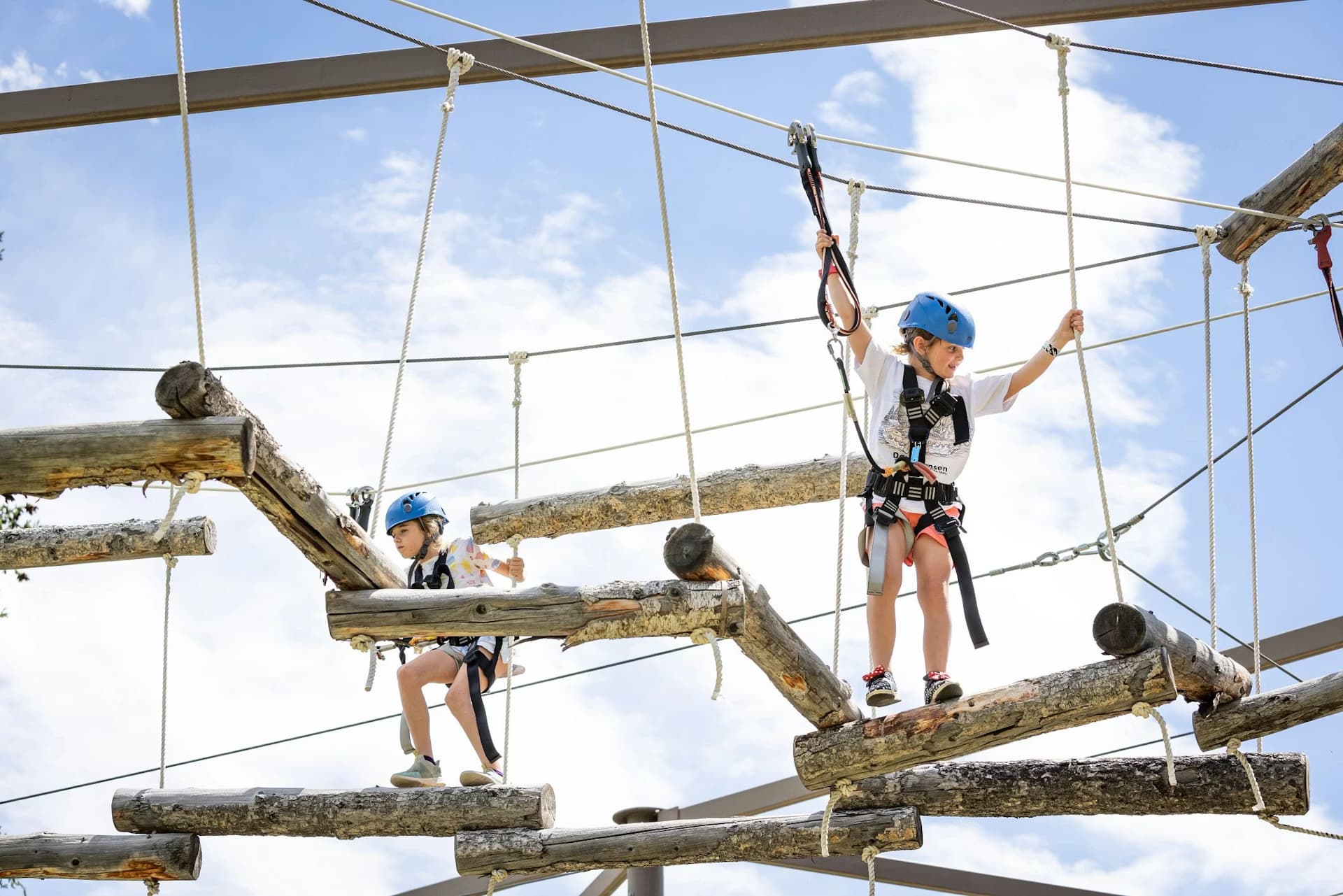 Kids navigating an elevated ropes course obstacle