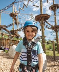 Smiling child in helmet and harness at a ropes course adventure park
